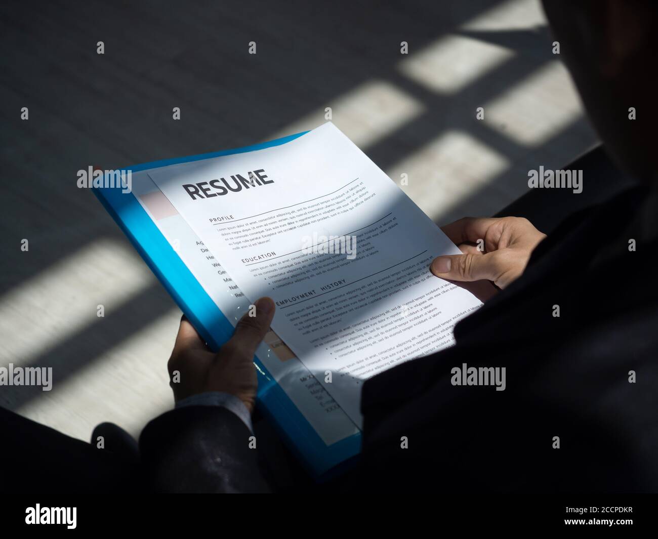 Unemployed man apply for a job sitting in queue holding resume papers  waiting for job interview with sun light and shadow. 14041592 Stock Photo  at Vecteezy