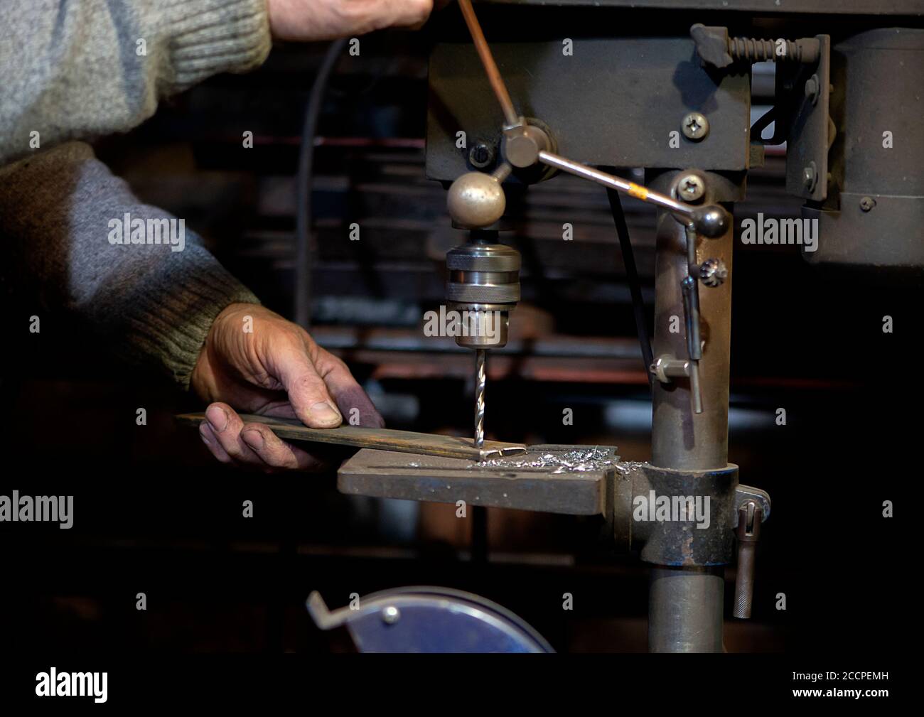 Blacksmith uses drill press in garage. A close up view of a metalworker