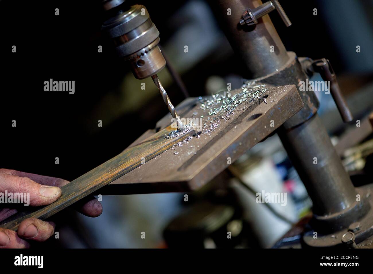 Blacksmith uses drill press in garage. A close up view of a metalworker