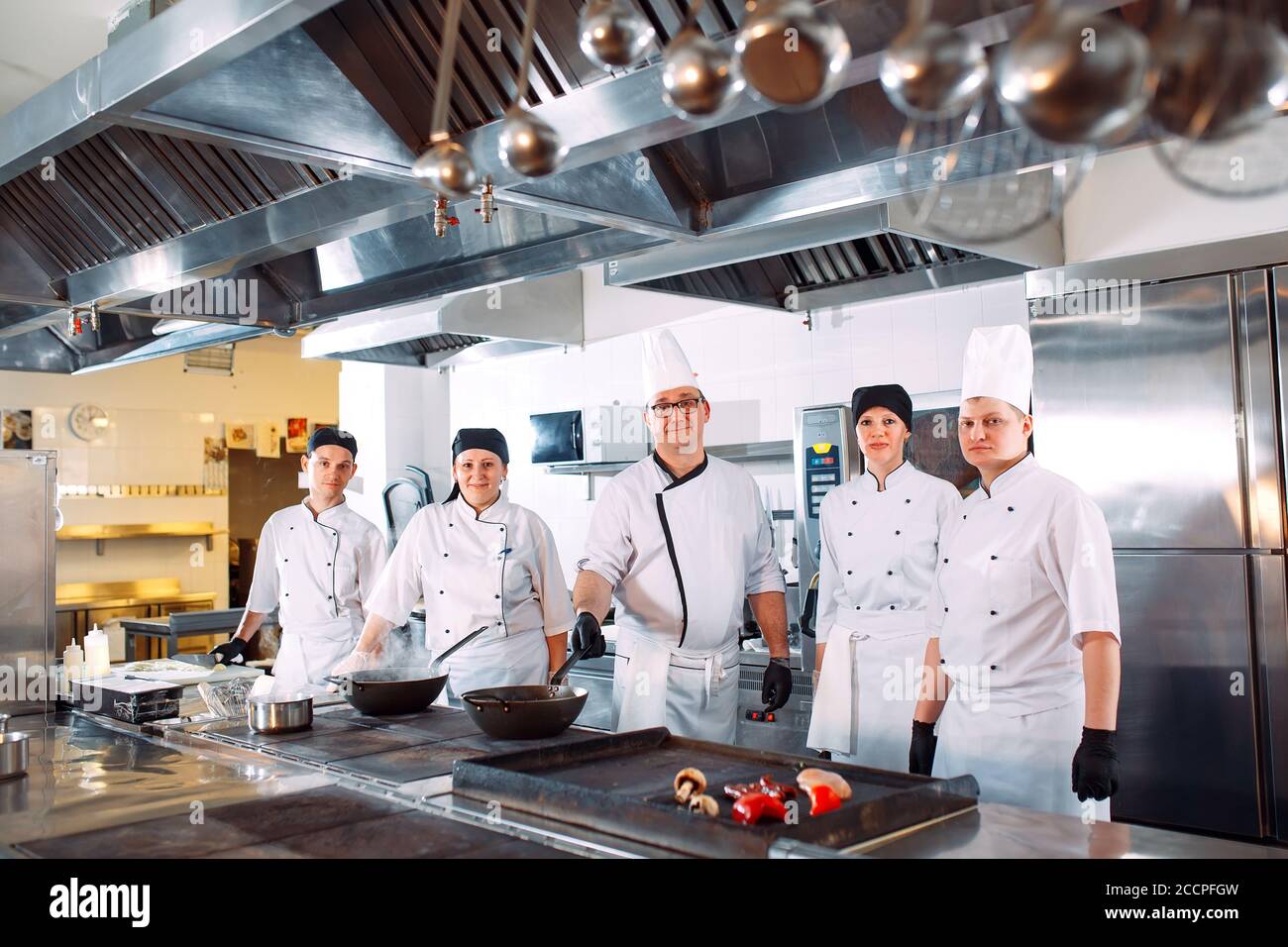 Five chefs wearing uniforms posing in a kitchen Stock Photo Alamy
