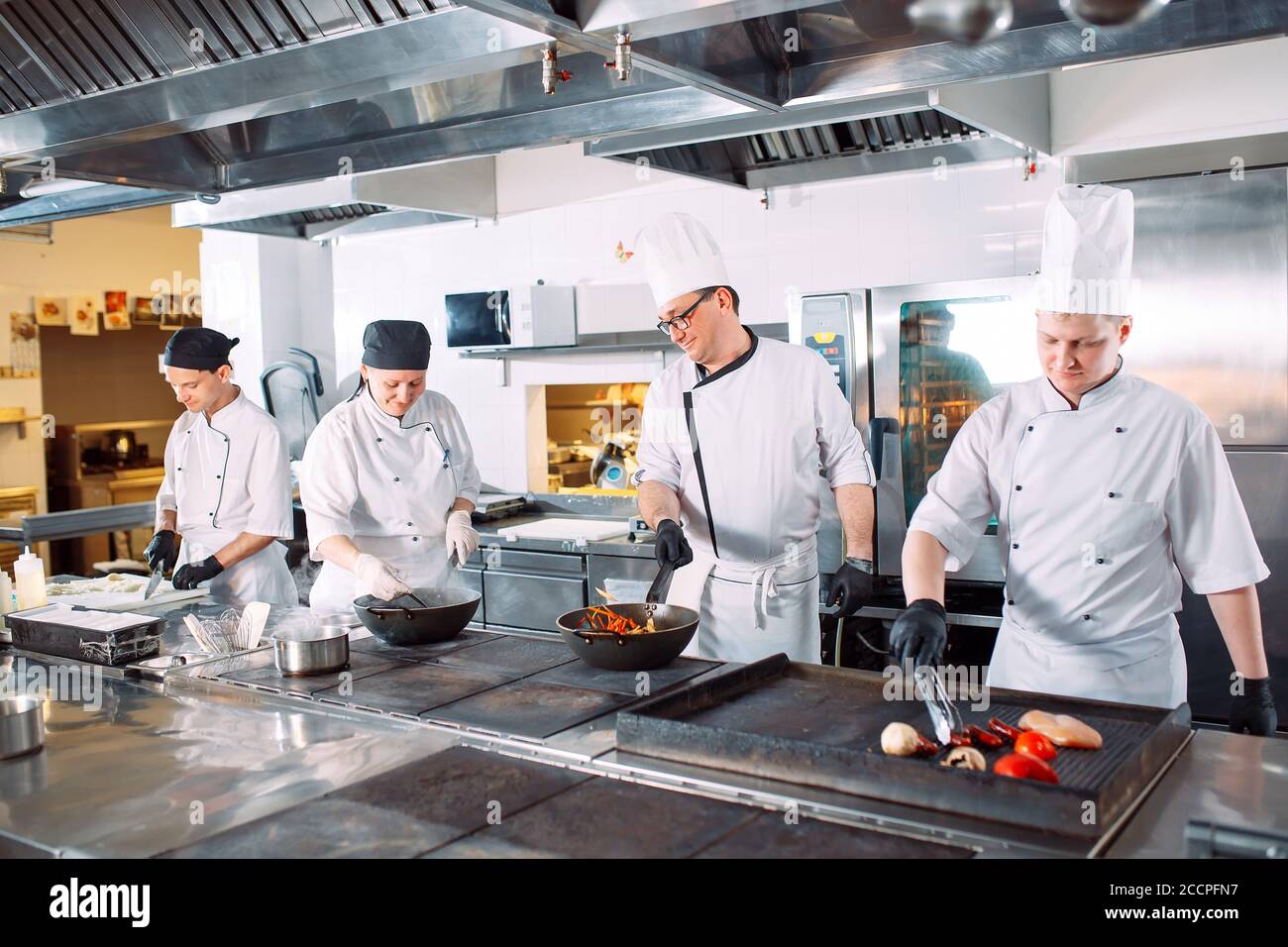 Five chefs wearing uniforms posing in a kitchen . Stock Photo