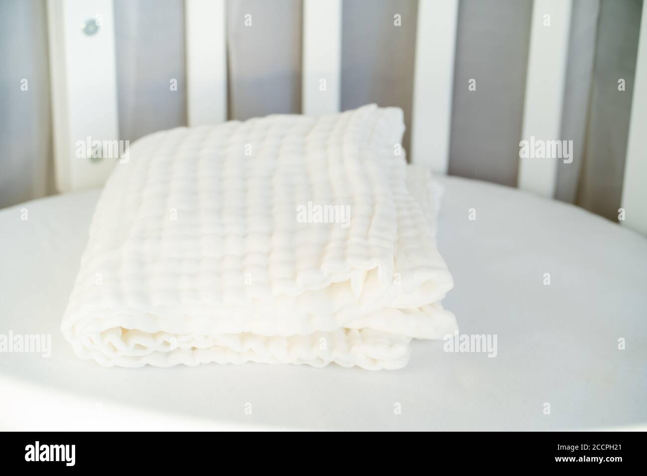 Soft white muslin blanket on the cot closeup Stock Photo