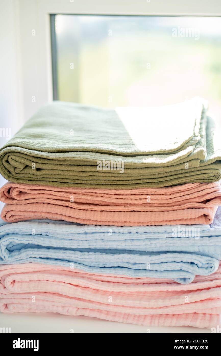 Colorful blankets on the windowsill in a stack, closeup Stock Photo