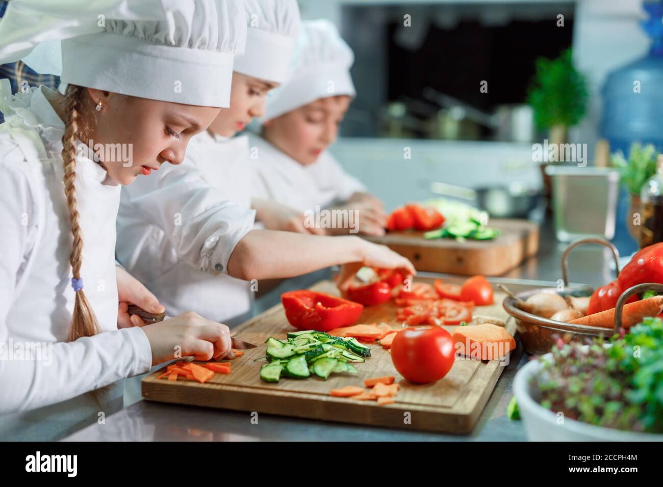 Children grind vegetables in the kitchen of a restaurant Stock Photo