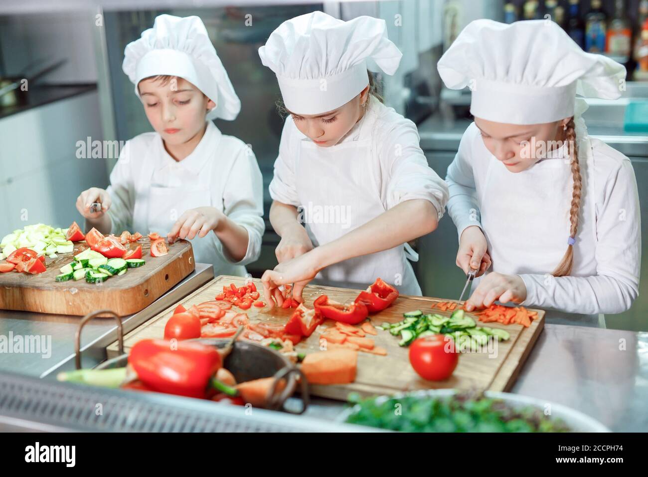 Children grind vegetables in the kitchen of a restaurant Stock Photo