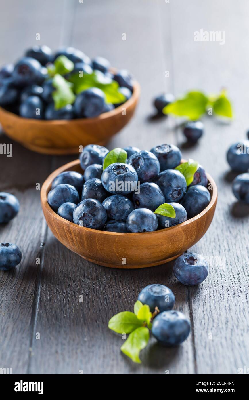 Fresh organic blueberry in bowl on wooden background. Healthy food concept, juicy wild forest berries. Stock Photo