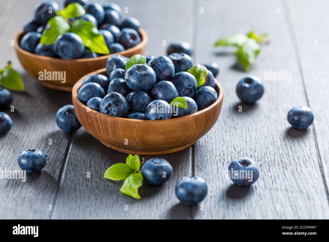 Fresh organic blueberry in bowl on wooden background. Healthy food concept, juicy wild forest berries. Stock Photo