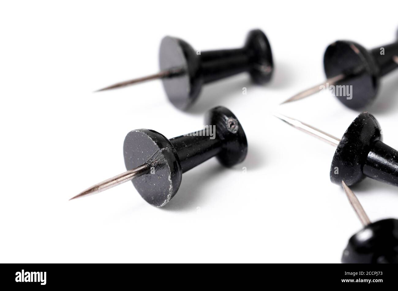 Close-up of black pins, tacks or thumbtacks with metal spiky tip, isolated on white surface or background, flat lay, indoors, studio Stock Photo