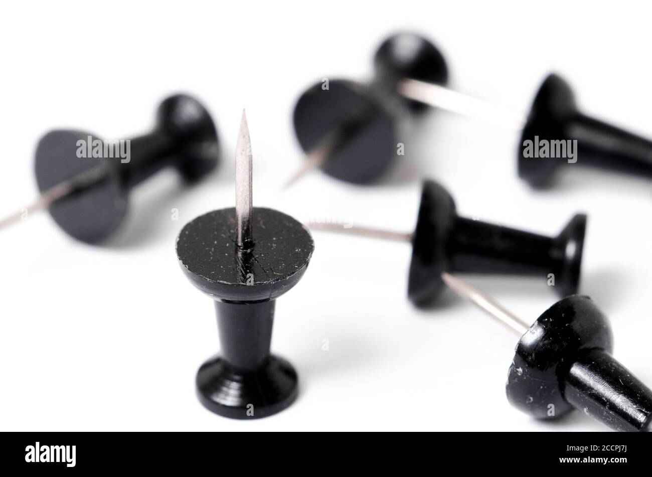 Close-up of black pins, tacks or thumbtacks with metal spiky tip, isolated on white surface or background, flat lay, indoors, studio Stock Photo