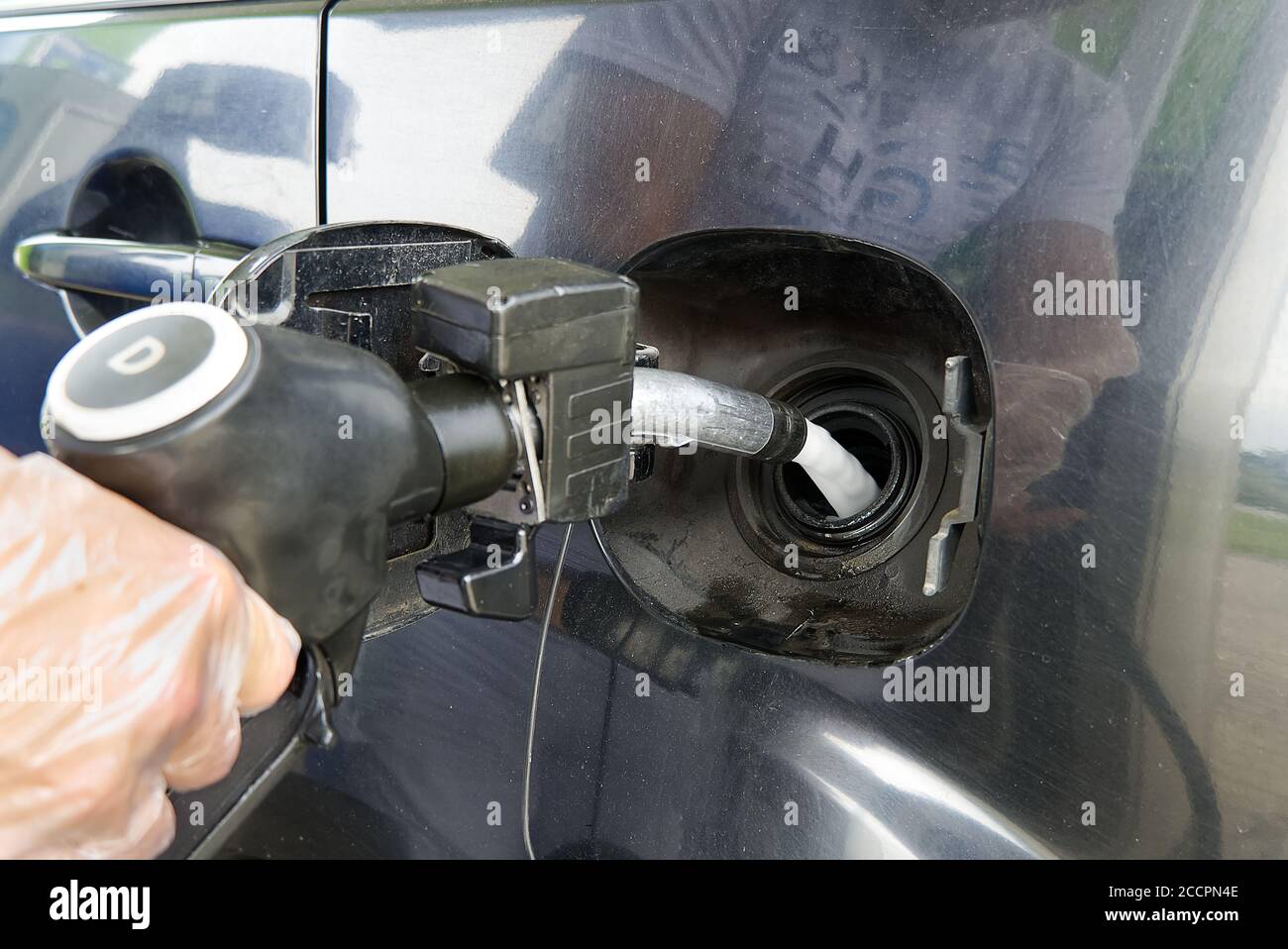 a man refueling a black car with diesel fuel at a gas station