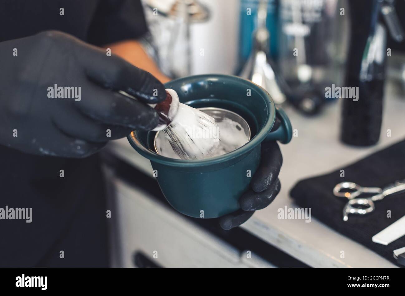 barber wearing black latex gloves preparing shaving cream Stock Photo