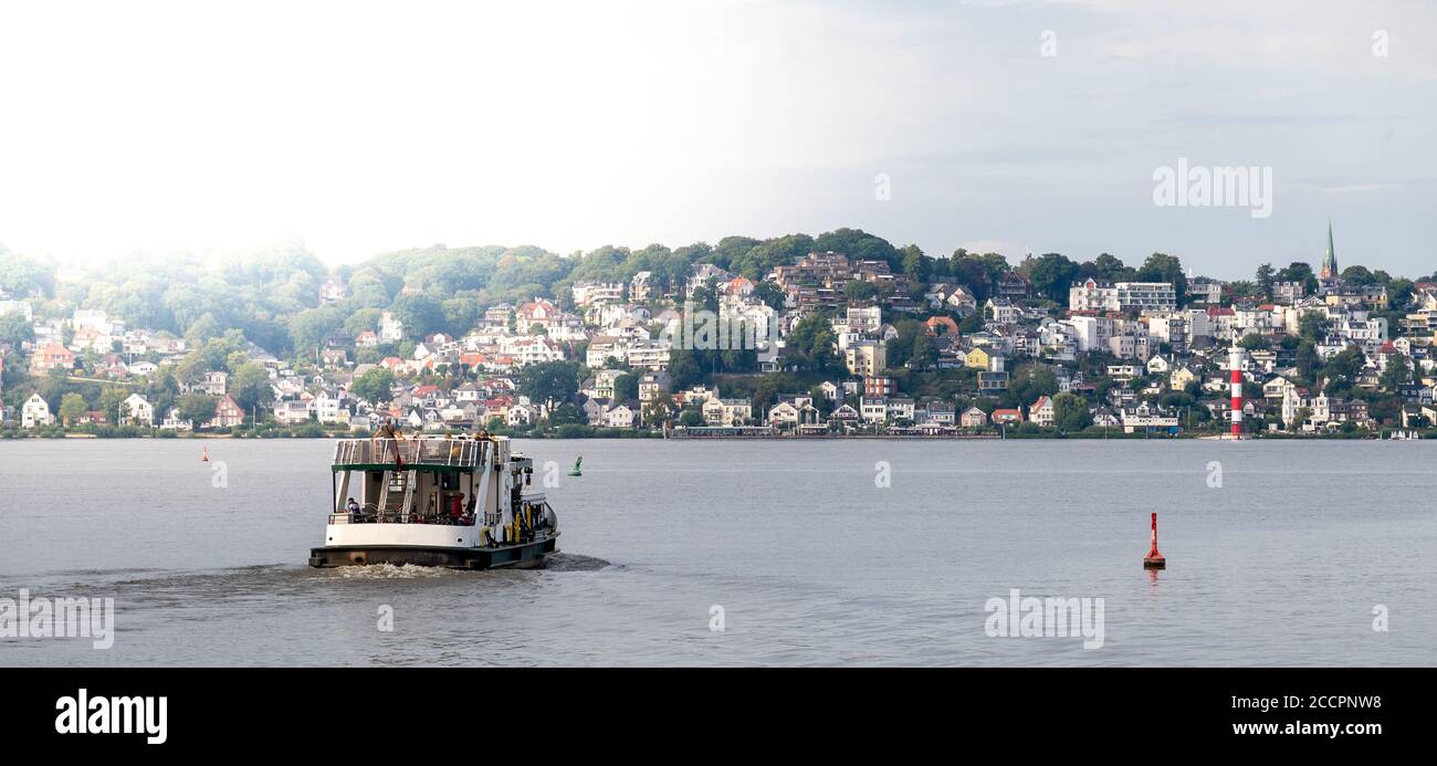A public transportation ferry is crossing the river Elbe and heading towards the district Blankenese of Hamburg, Germany. Stock Photo