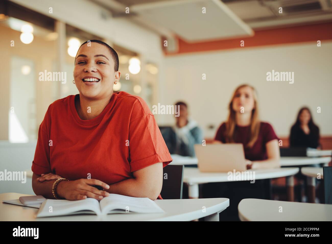 Female student sitting in university classroom and smiling. Woman paying attention in the class. Stock Photo
