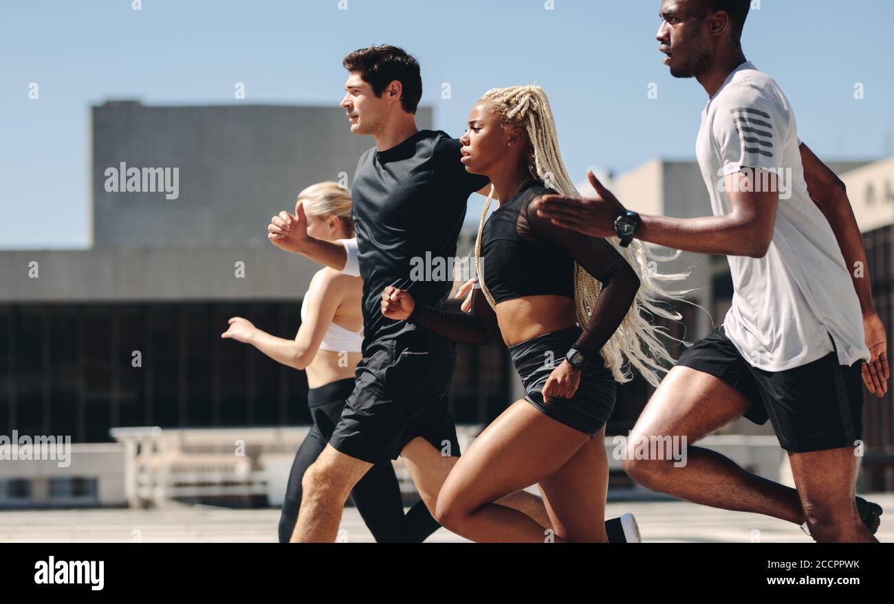 Healthy people running together in city. Runners training together outdoors in morning. Stock Photo