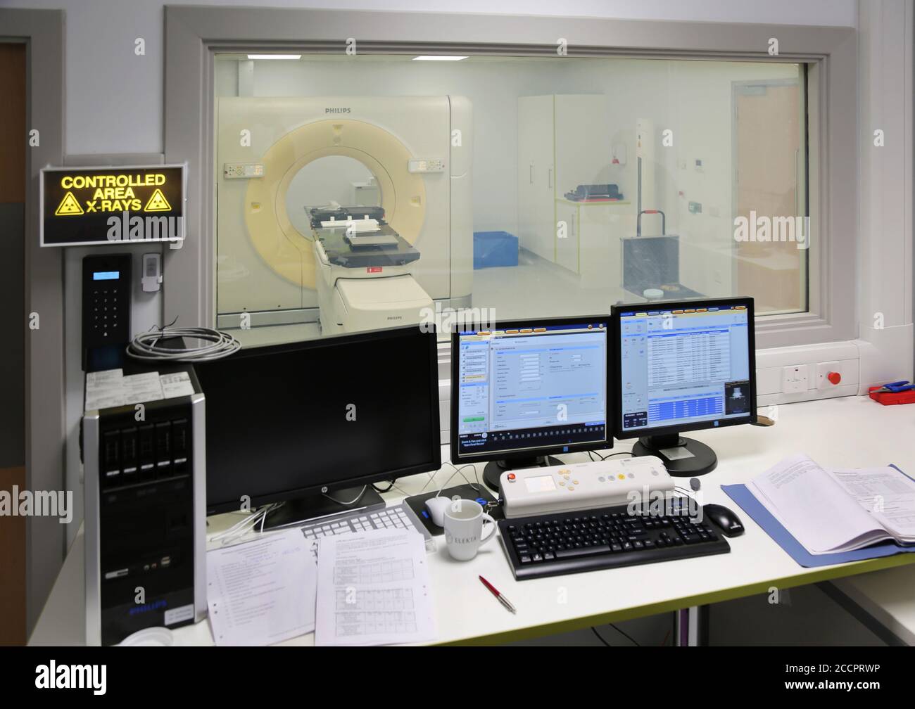 New CT Scanner constrol desk shown during comissioning, scanner visible beyong the protective window. Eastbourne District General Hospital. Stock Photo