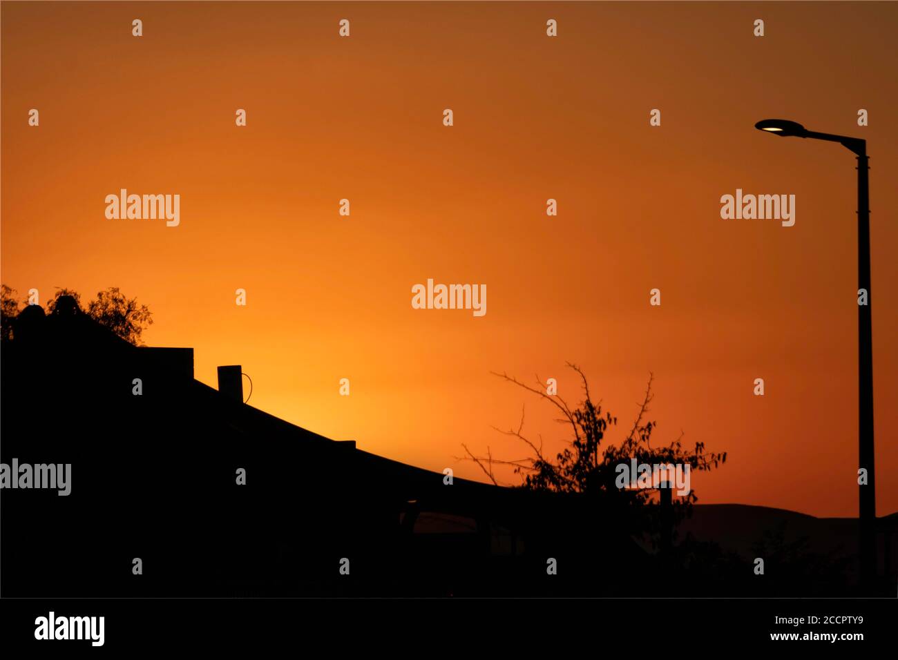 Silhouettes of the houses and trees on the background of the colorful sunset sky Stock Photo