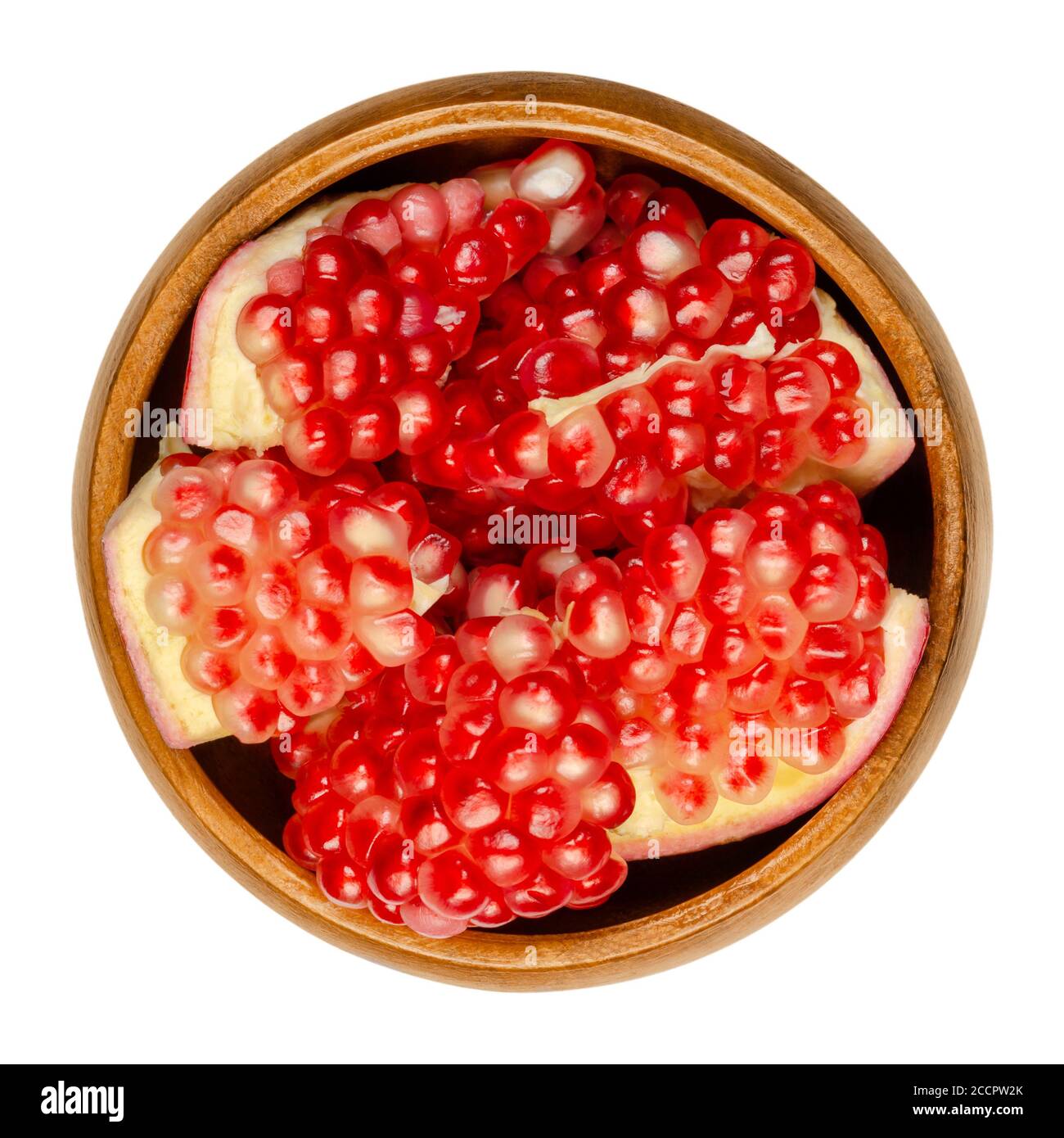 Pomegranate clusters in a wooden bowl. Punica granatum. Fruit with red to purple seed clusters. Can be eaten fresh, juiced, or used to make grandine. Stock Photo