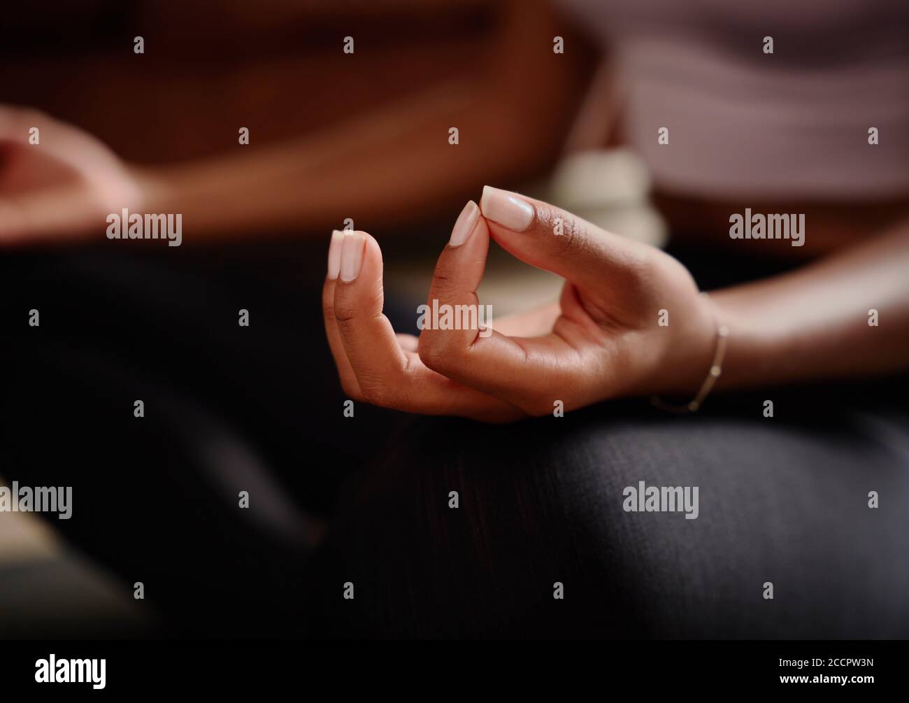 Closeup of young female hand mudra while sitting in lotus position and meditating Stock Photo