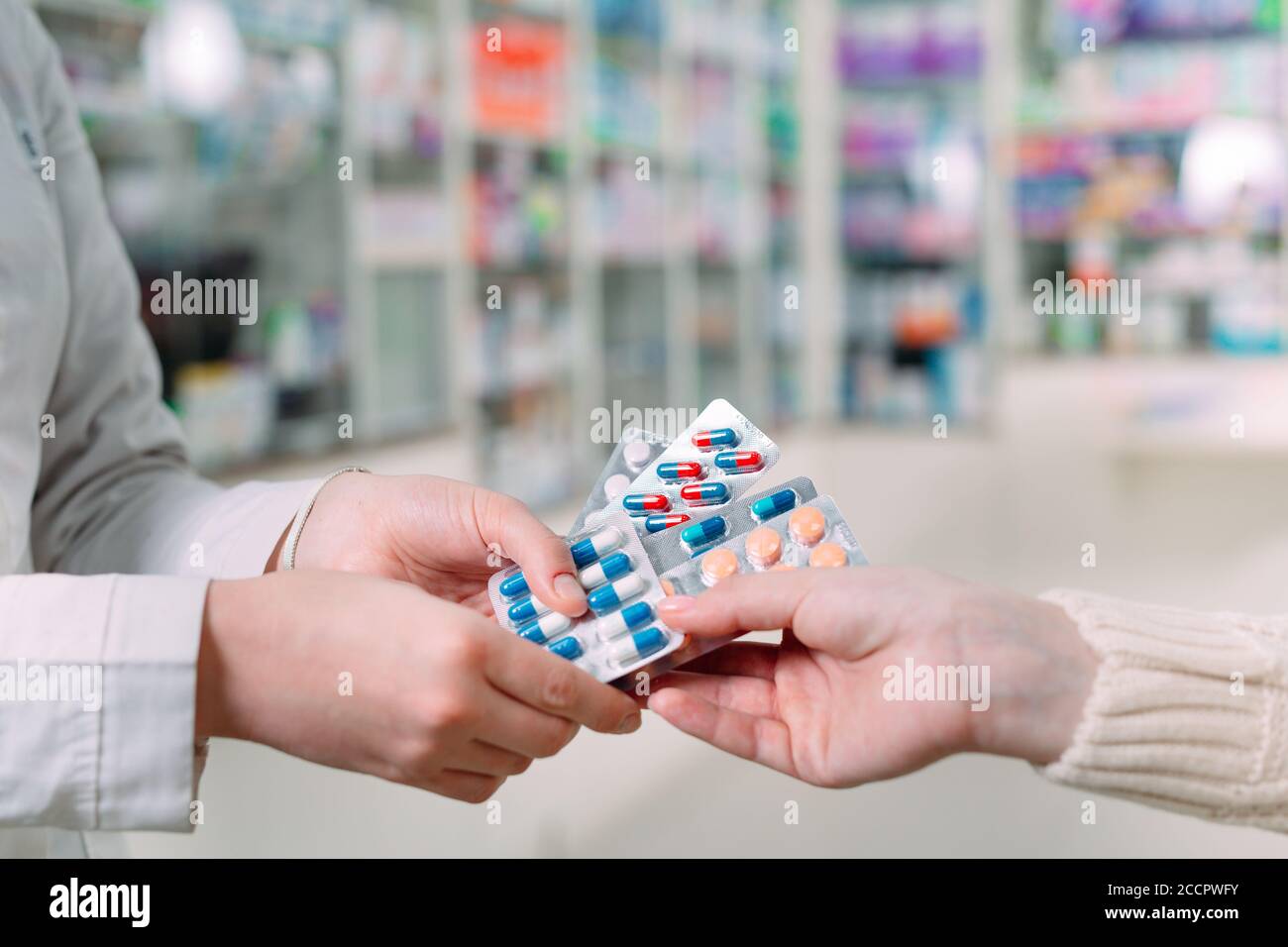 Close up of a girl hands buying pills in a pharmacy. Stock Photo