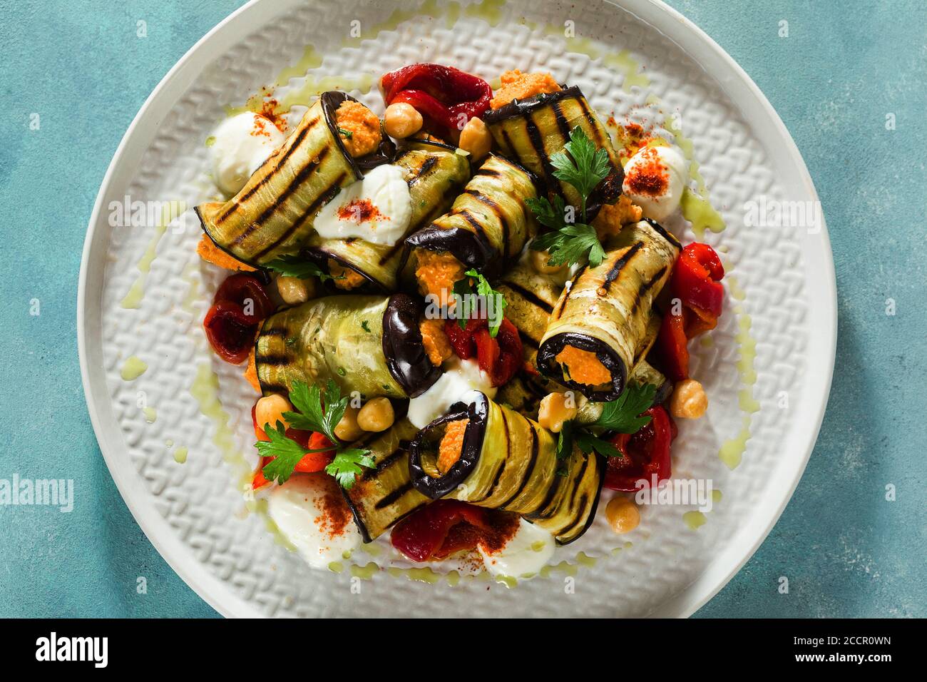grilled eggplant wrap with red bell pepper hummus and spicy yogurt on the table. delicious vegan