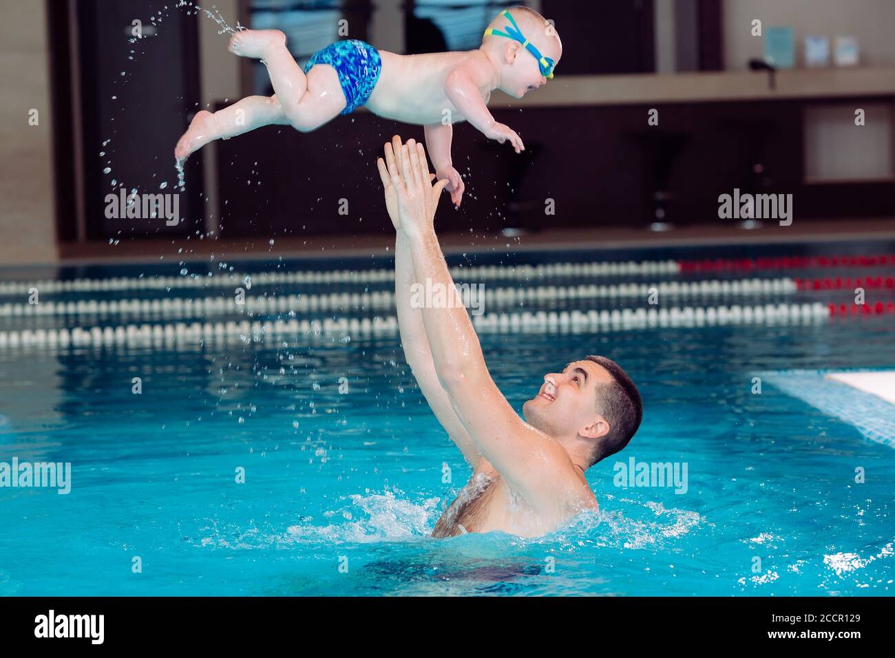 Father and son play in the pool. the father throws the son Stock Photo