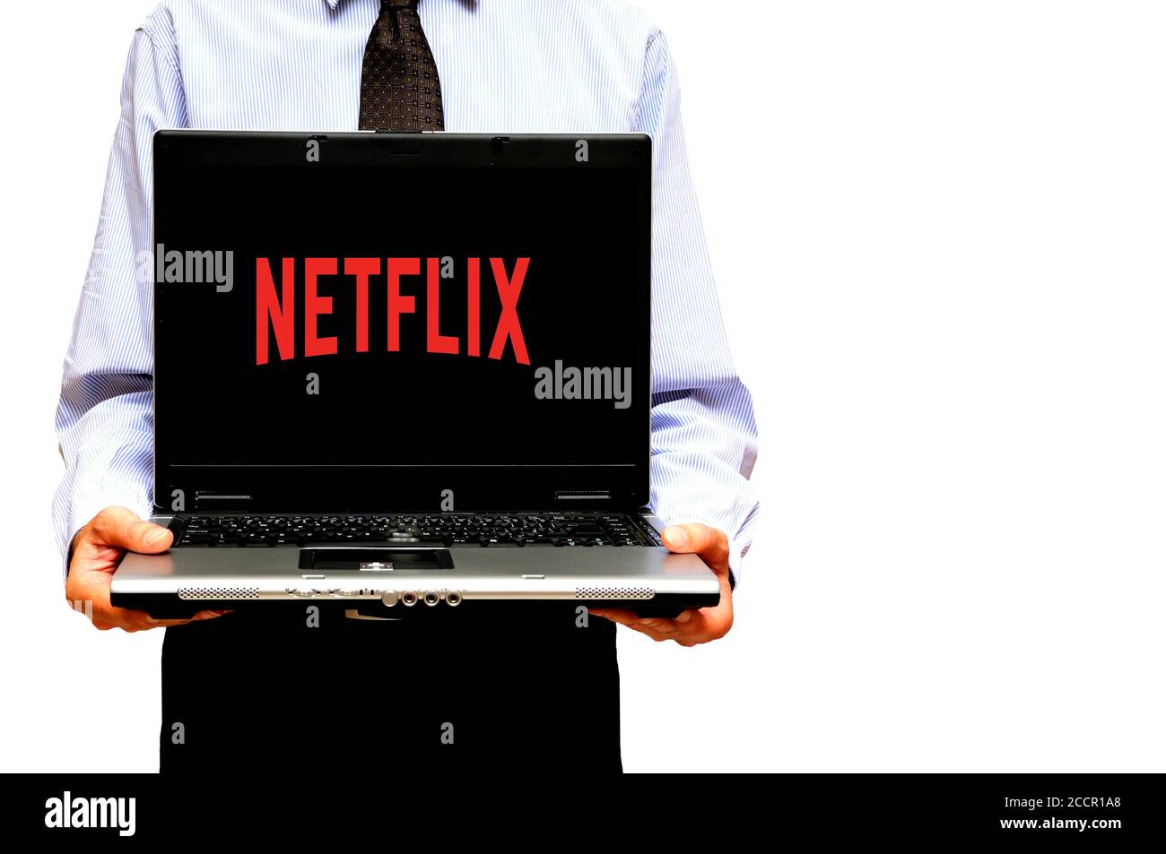 man holding a laptop with a logo of Netflix streaming service on the screen Stock Photo