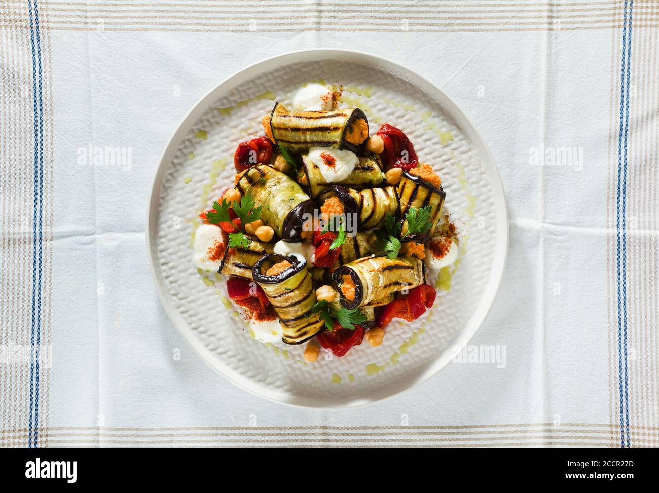 grilled eggplant wrap with red bell pepper hummus and spicy yogurt on the table. delicious vegan