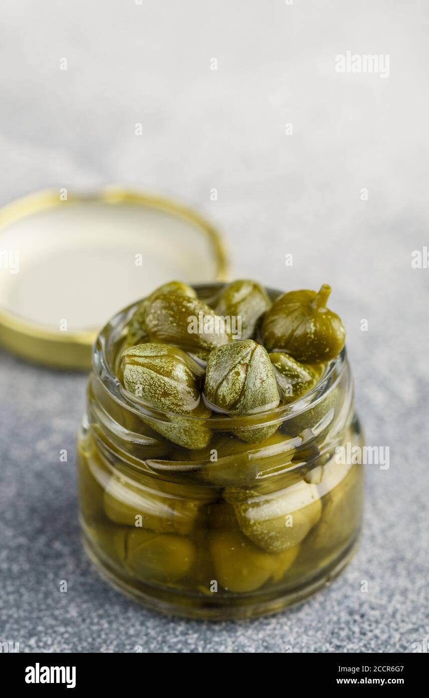 Pickled or salted capers in a glass jar close-up. Unopened flower buds ...