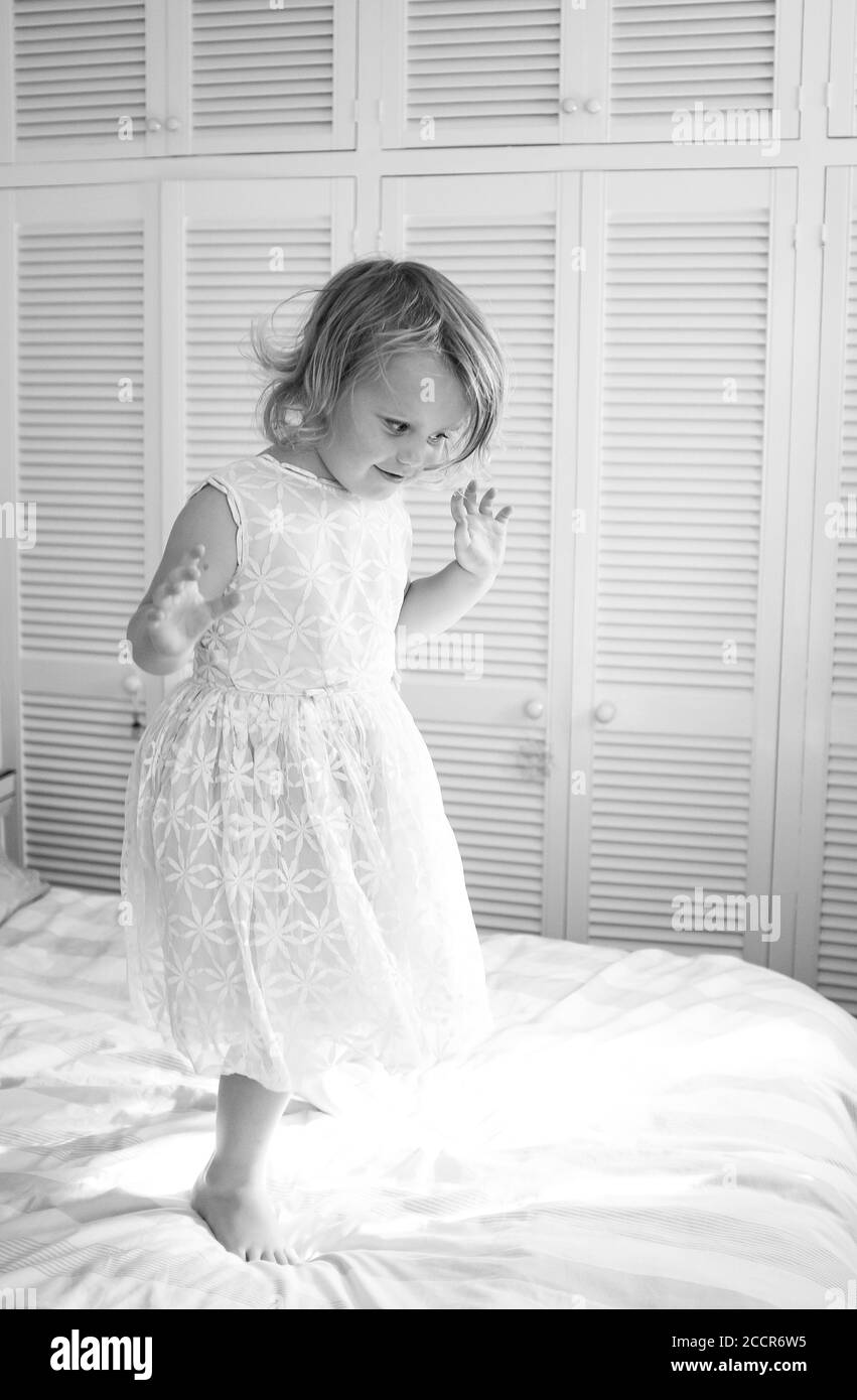 Young child female 3 years old dressing up in an old bridesmaid dress originally worn by her grandmother 56 years earlier Stock Photo