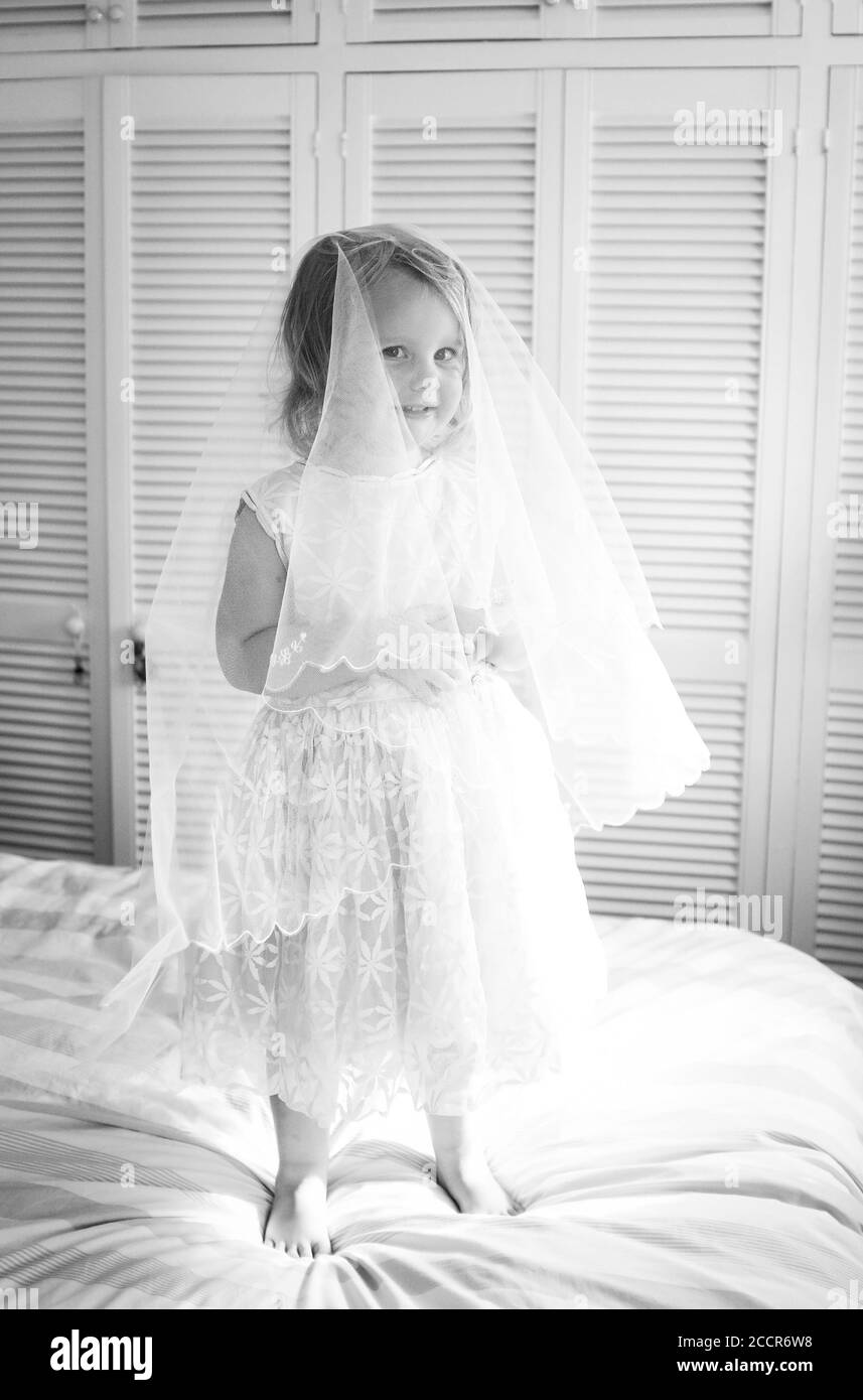 Young child female 3 years old dressing up in an old bridesmaid dress originally worn by her grandmother 56 years earlier Stock Photo