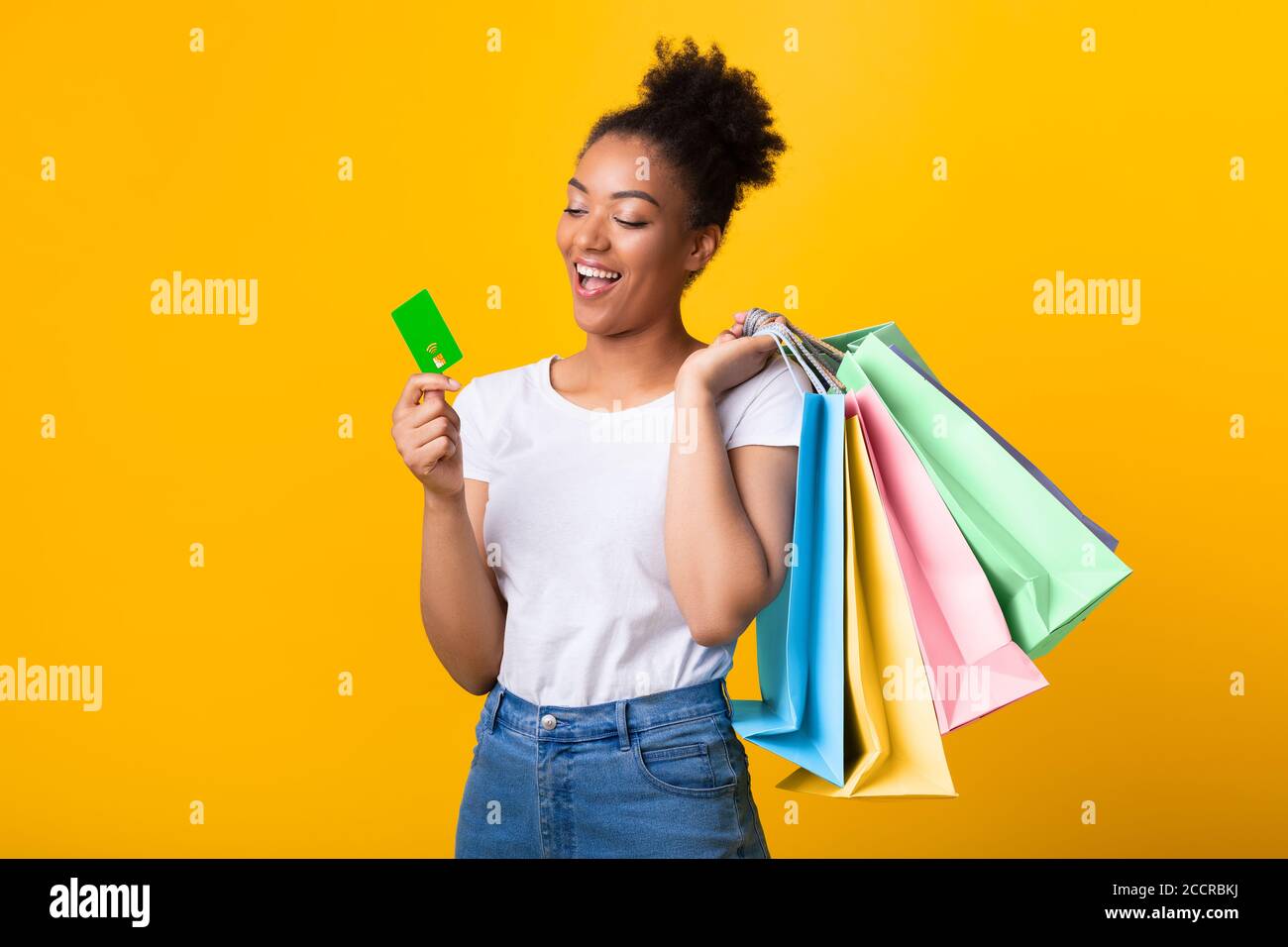 Cheerful afro woman with shopping bags and plastic card Stock Photo