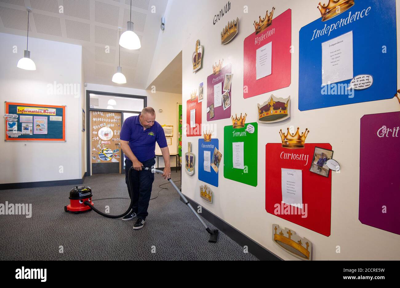 Site manager Mark Lee hoovers the corridors Queen's Hill Primary School in Costessey near Norwich, as they prepare to reopen. Stock Photo