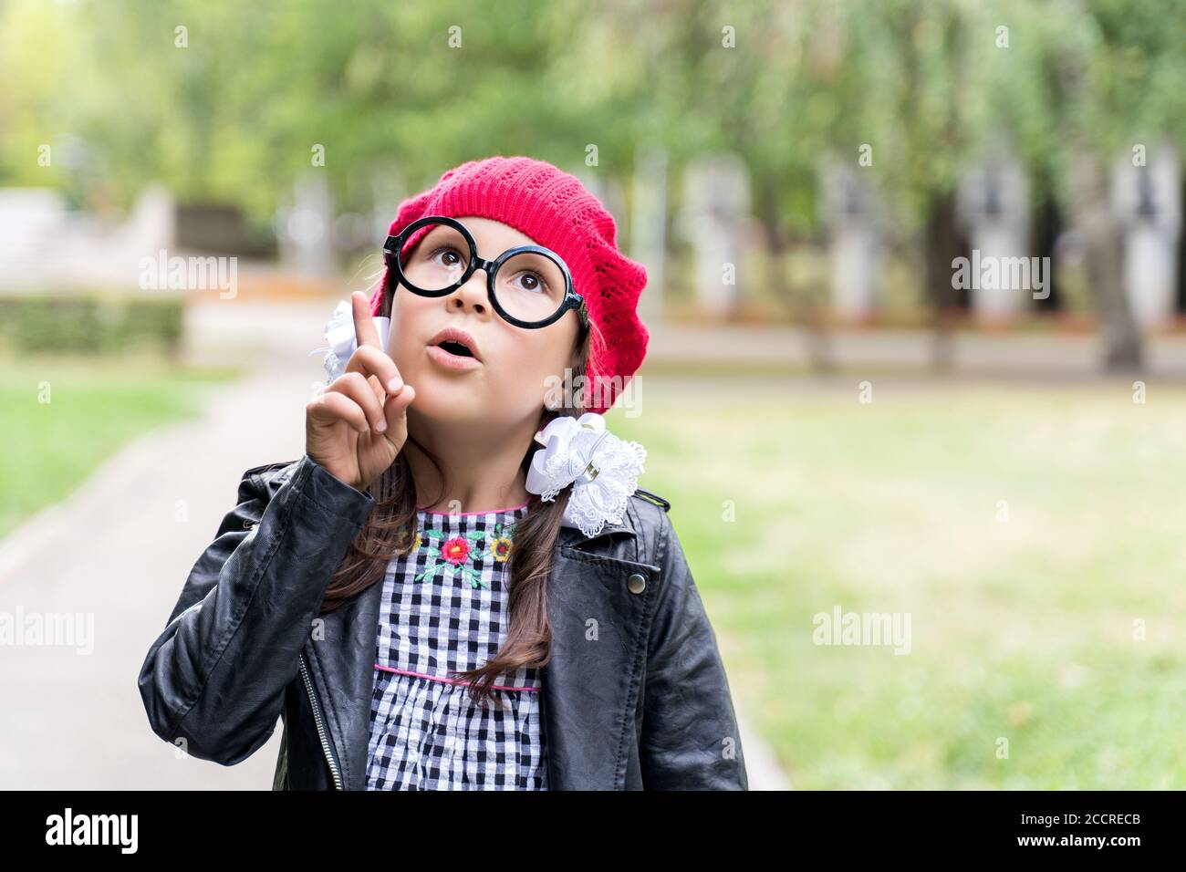 a funny little girl in a red cap holds up her finger . I got an idea. Stock Photo