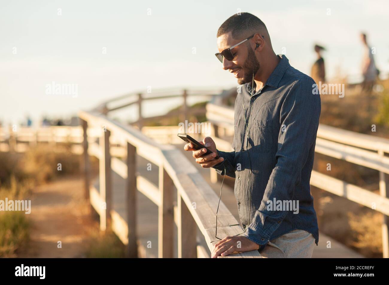 Latin man texting with a smartphone over an amazing sunset landscape view. Natural  outdoor light Stock Photo