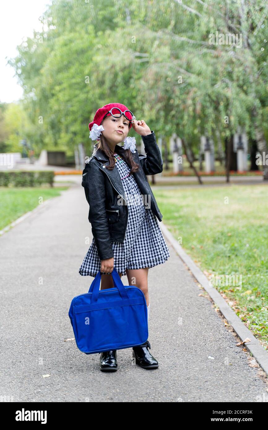 a little funny girl in a red cap and a briefcase goes to school Stock ...