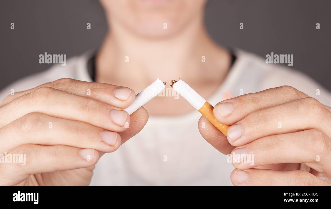 girl holding a broken cigarette in half close-up, harm from smoking, no smoking concept, bad habit, harm from nicotine. Stock Photo
