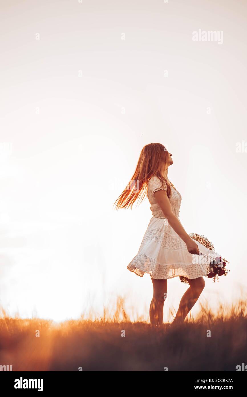 Outdoors photo of young, teen, ginger girl running through the field, holding a summer hat. Copy space Stock Photo