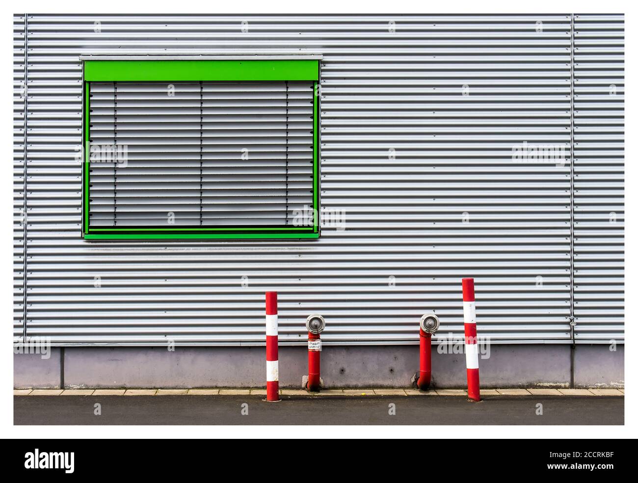 Sunny scenery of a building rough white wall with green window frame Stock Photo