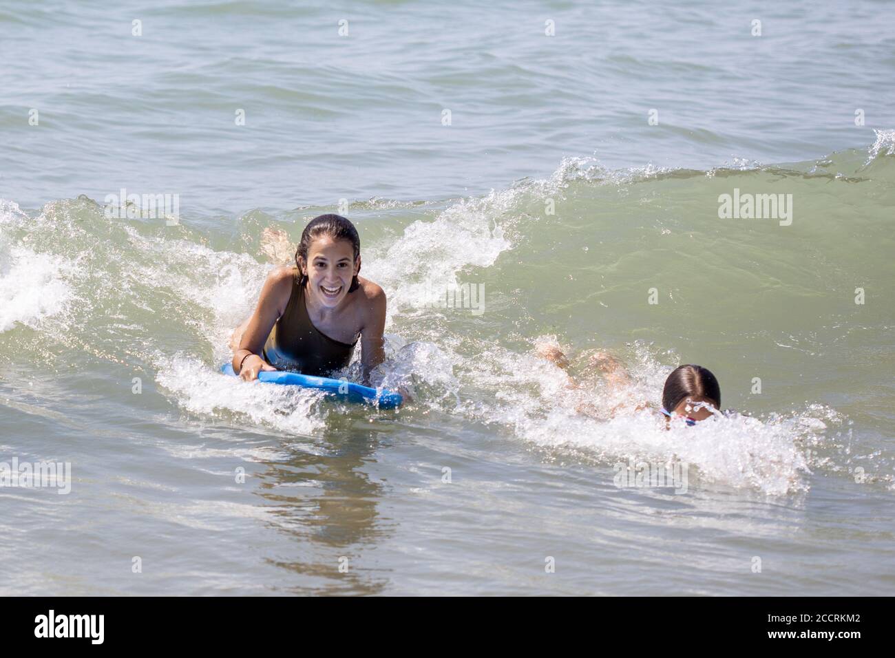 Two happy girls surfing and having fun with the bodyboard on the beach