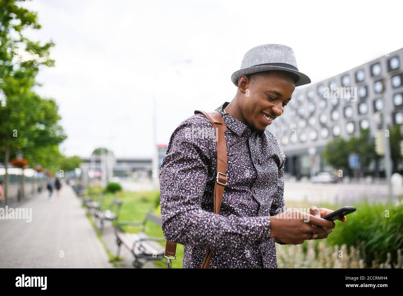 Young black man commuter with smartphone outdoors in city, walking. Stock Photo