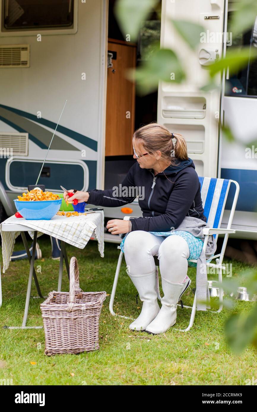 Woman sitting in front of a camping car with chanterelles. Stock Photo