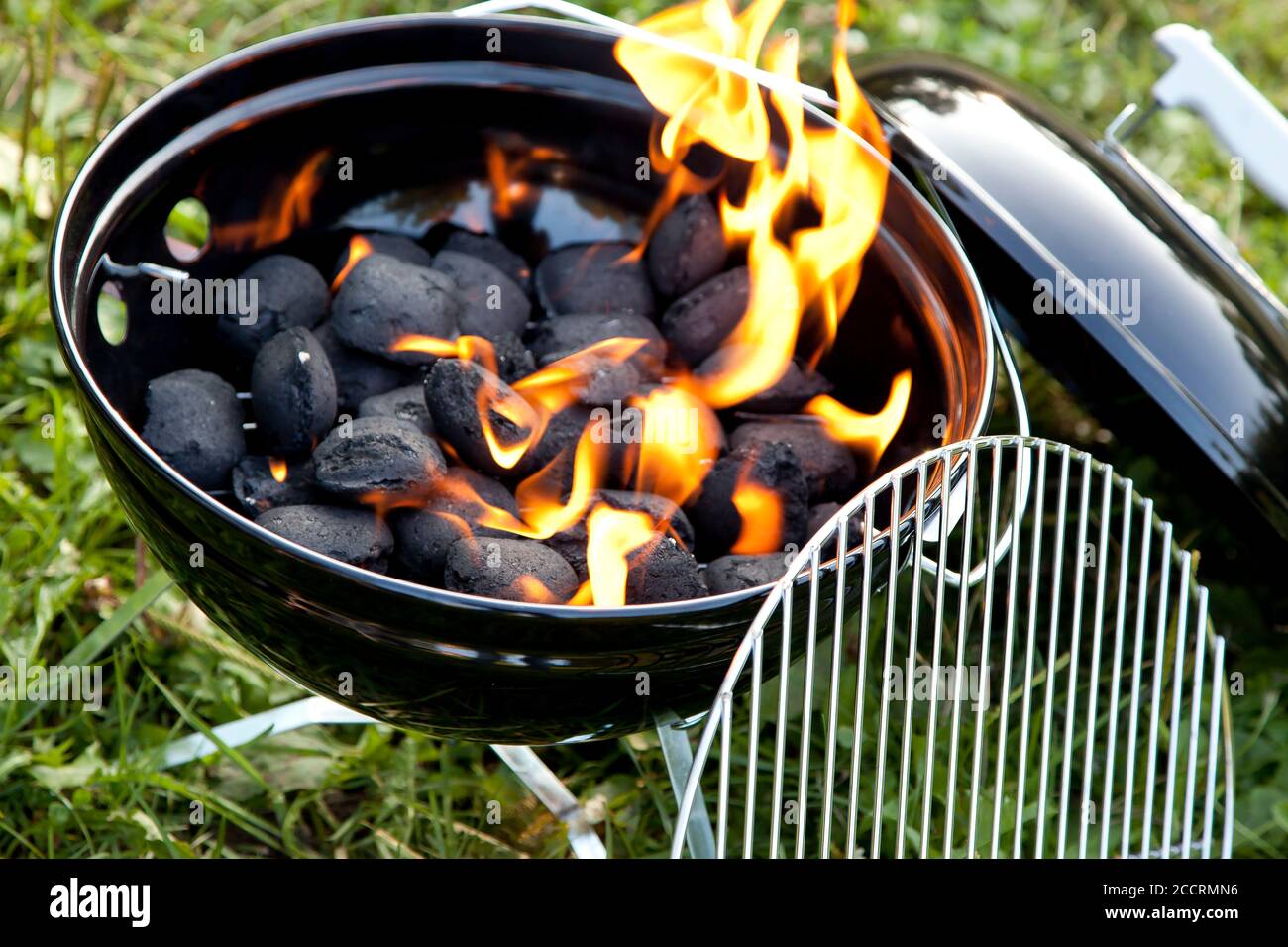 The charcoal in the grill is on fire and the flames are orange. Stock Photo