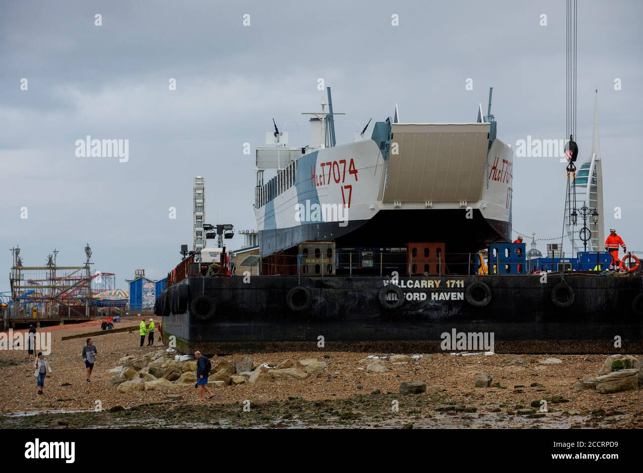 Portsmouth, Hampshire, UK. 24th Aug 2020. Bystanders photograph the LCT 7074, the last surviving amphibious landing craft tank, before it is moved to the D-Day Museum in Portsmouth, Monday August 24, 2020.  The craft which originally carried tanks and soldiers to Normandy, was floated by barge from the National Museum of the Royal Navy, where it was being restored, to the Promenade in Southsea, where a crane built a bridge to the barge, so it could be driven to its new home at the D-Day Museum.    Credit: Luke MacGregor/Alamy Live News Stock Photo