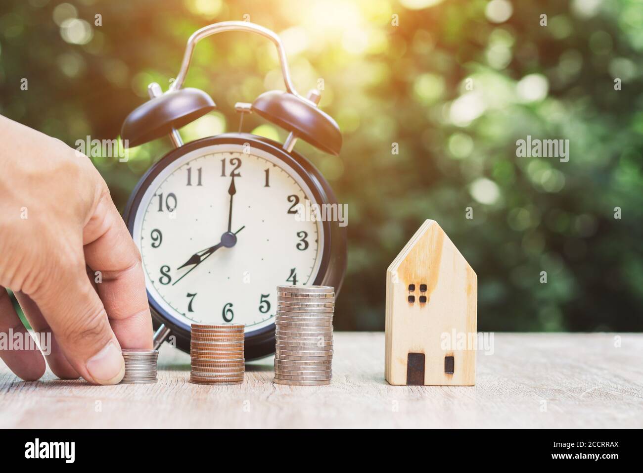 Close-up of male hand holding house model with green bokeh background saving money to prepare for the future. Stock Photo