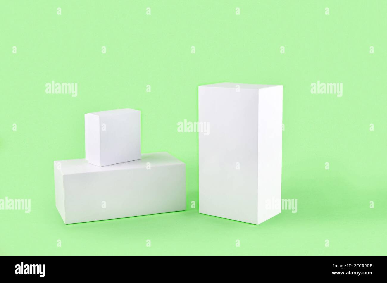 Three white geometric figure, a rectangular with shadows on a light green background. Stock Photo