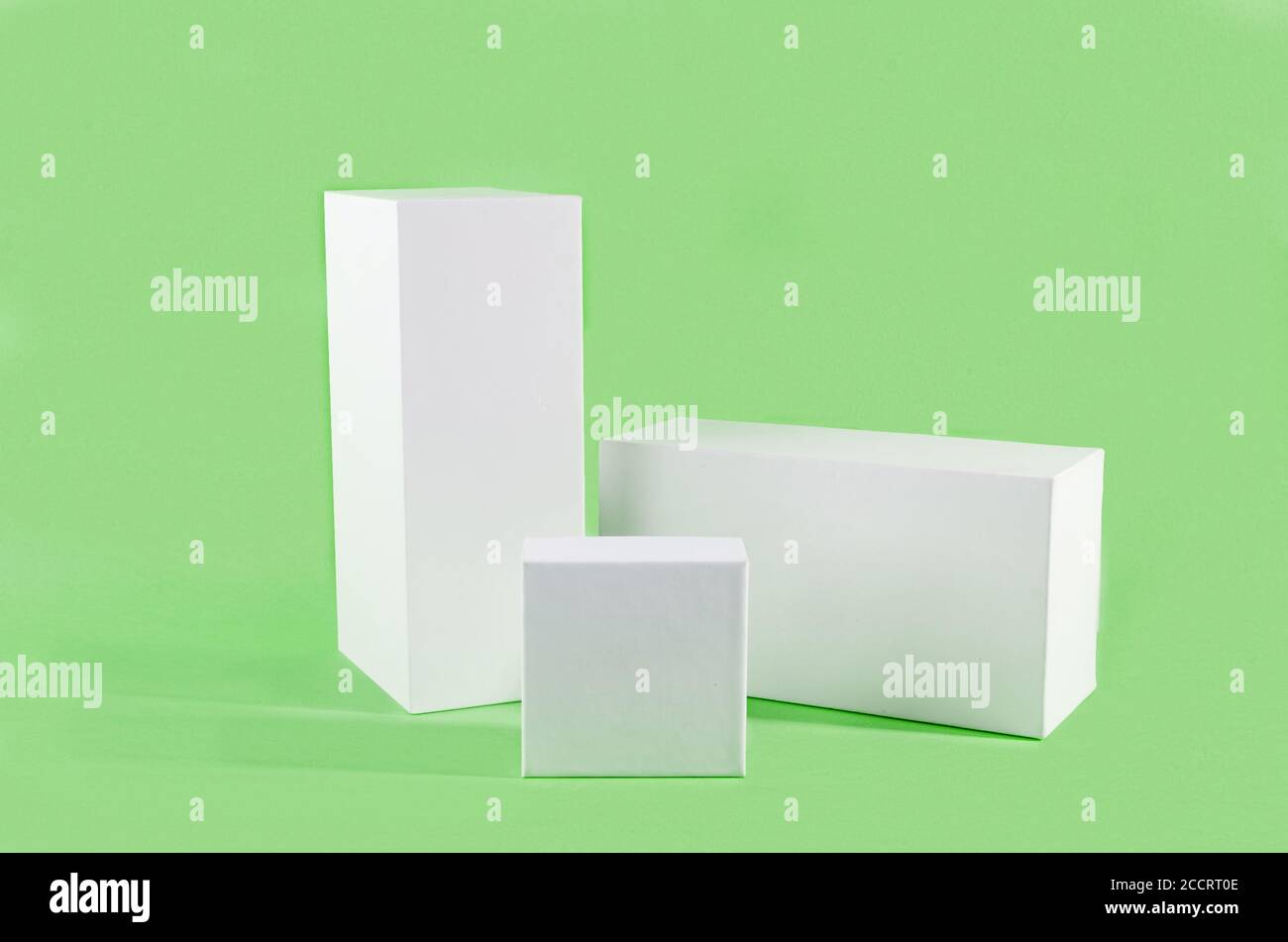 Three white geometric figure, a rectangular with shadows on a light green background. Stock Photo