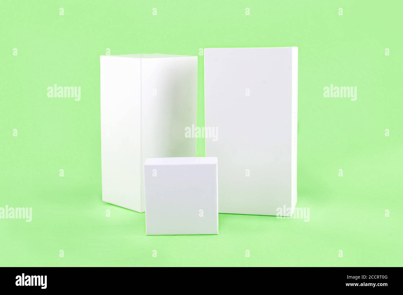 Three white geometric figure, a rectangular with shadows on a light green background. Stock Photo