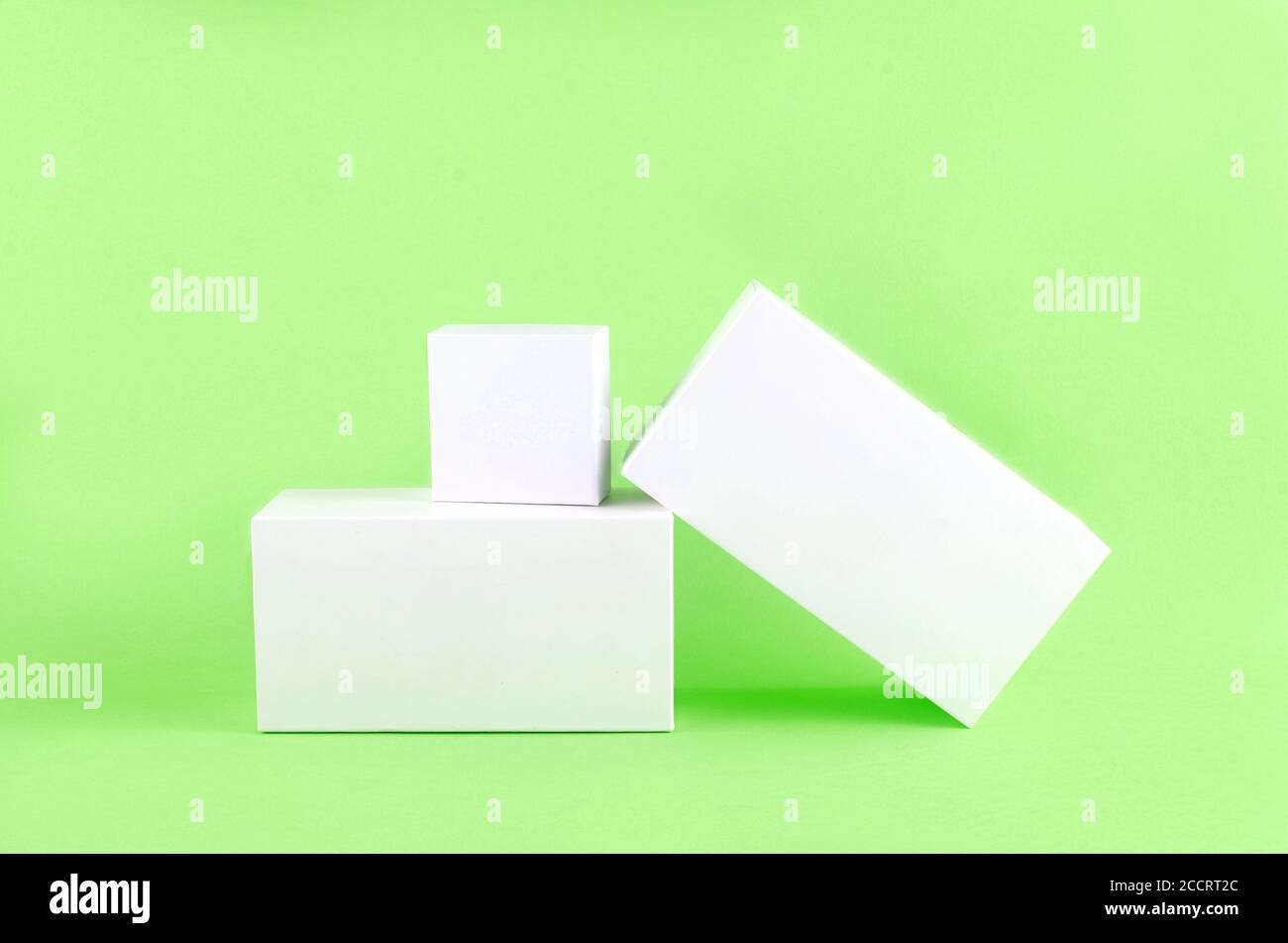 Three white geometric figure, a rectangular with shadows on a light green background. Stock Photo