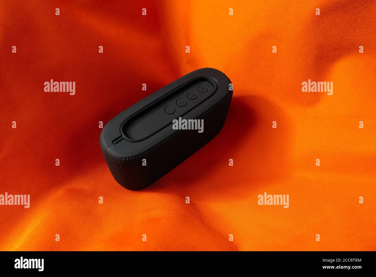 Small black wireless speaker on orange background Stock Photo