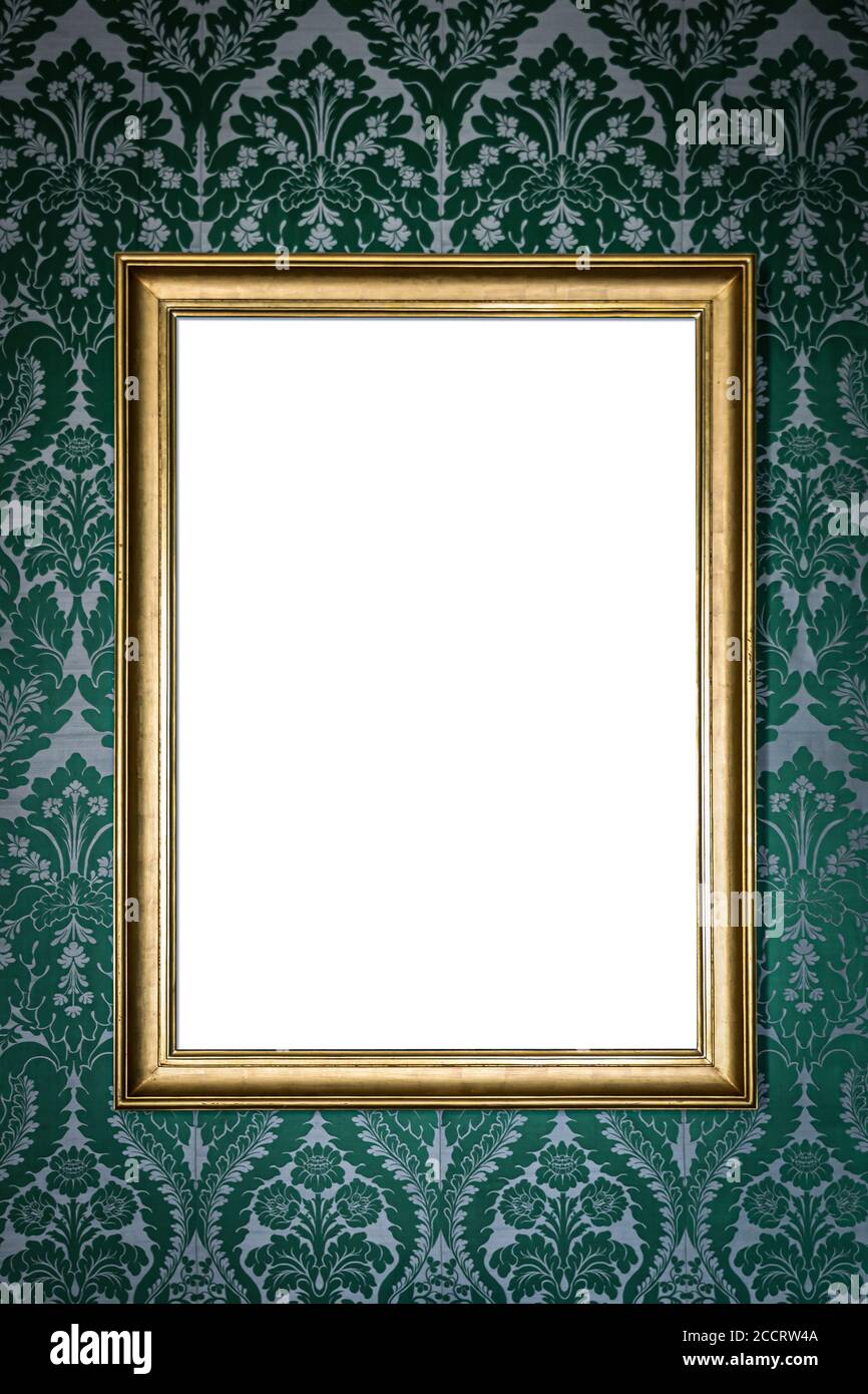 blank golden picture frame hanging on wall on green floral vintage wallpaper Stock Photo